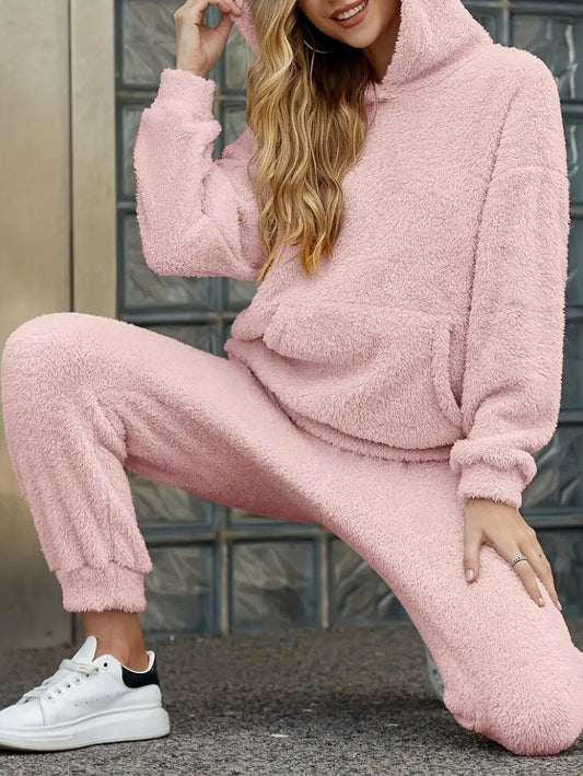 Person wearing a pink fleece tracksuit with white sneakers.