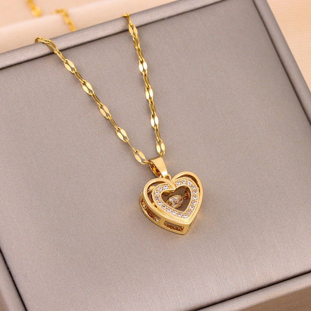 Gold heart-shaped necklace with a pendant on a gray surface