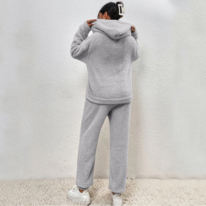 Person wearing a gray fleece tracksuit against a white wall.