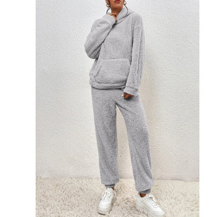 Person wearing a gray fleece tracksuit with white sneakers on a light background